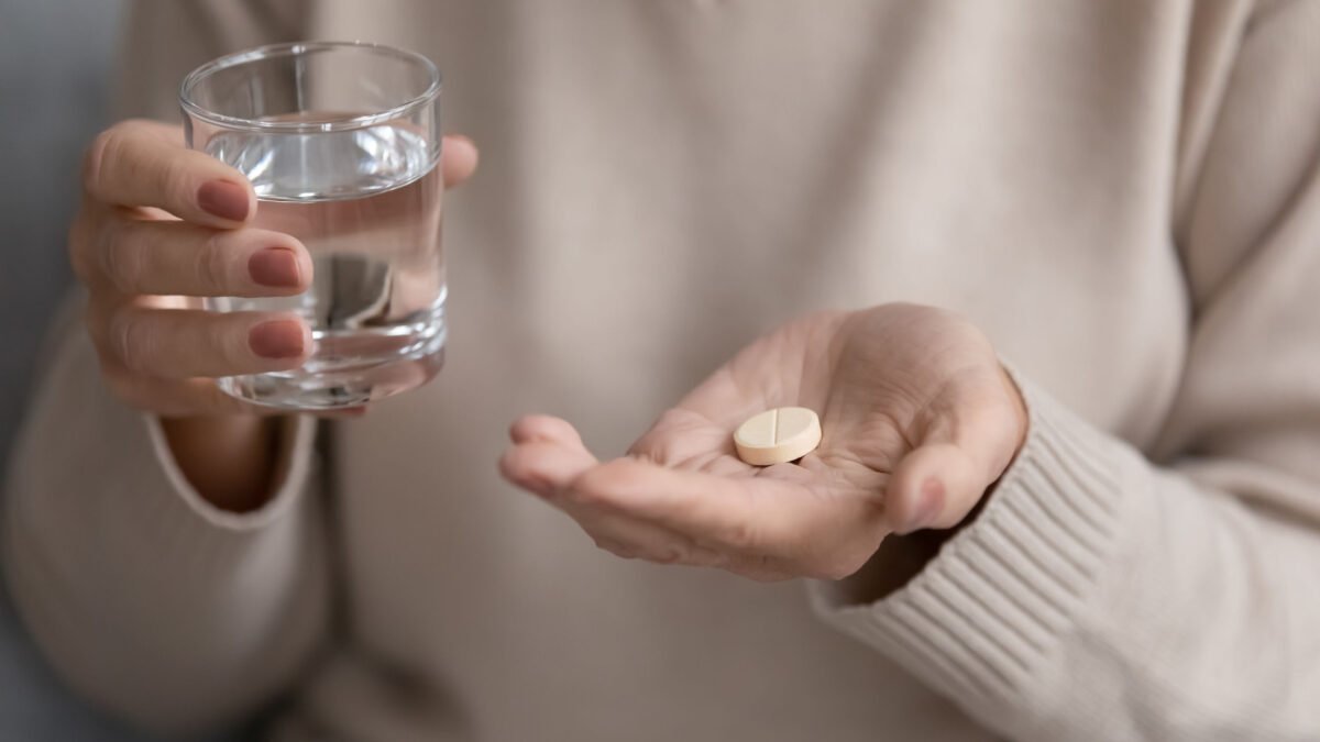 close up of a senior woman taking her medication at home with a glass of water